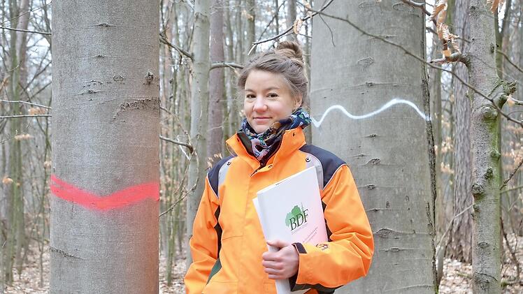 Miriam Janthur steht zwischen zwei verschieden markierten Bäumen.