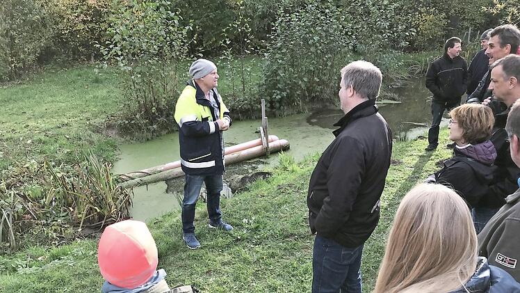 Gunther Haas erläutert Fachleuten und Nachbarn die Vorrichtung, die den Biber dazu bringt, dass er nicht weiterbaut.  Foto: Michael Busch