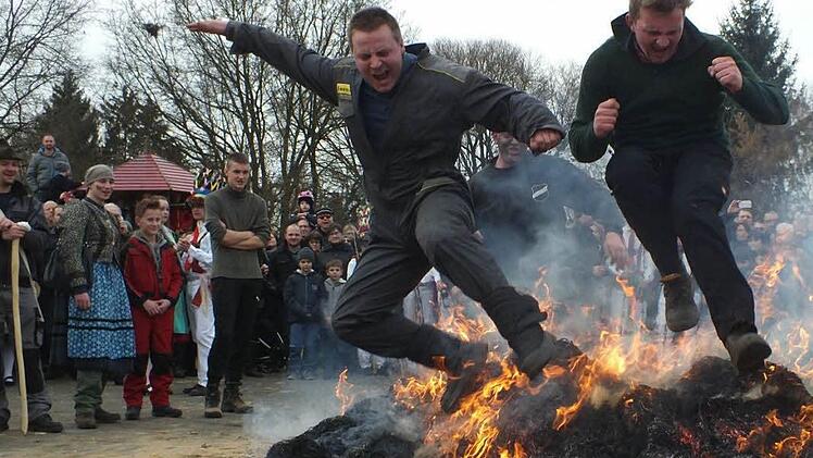Der Sprung über das heruntergebrannte Feuer aus den Strohbärenmonturen soll Glück bringen.