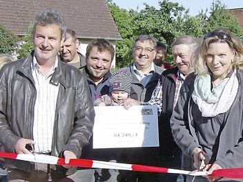 MIt einem beherztebn Schnitt wird das rot-weiße Absperrband durchtrennt. Damit ist der neu gestaltete Dorfplatz in Lilling offiztiell seiner Bestimmung übergeben.  Foto: Malbrich