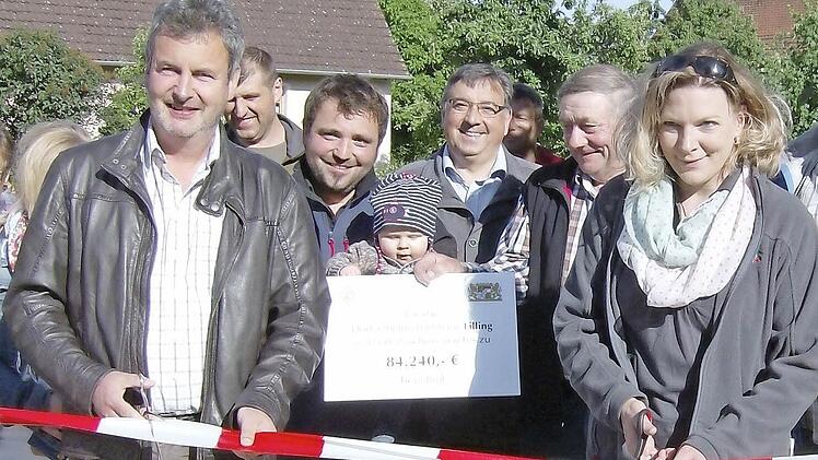 MIt einem beherztebn Schnitt wird das rot-weiße Absperrband durchtrennt. Damit ist der neu gestaltete Dorfplatz in Lilling offiztiell seiner Bestimmung übergeben.  Foto: Malbrich