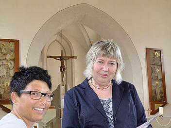 Der handliche kleine Kirchenführer ist fertig. Elfriede Oppel (rechts) zeigt ihn der Pfarrgemeinderatsvorsitzenden Claudia Benkert. Im Hintergrund ist das Geburtstagskind zu sehen: das 500 Jahre alte Riemenschneider-Kruzifix. Fotos: Kathrin Kupka-Hahn