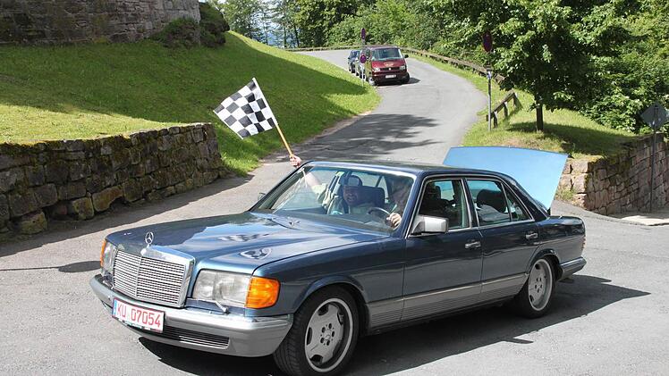 Mönch Throsten Schlensog lässt sich fahneschwenkend im edlen Benz auf die Burg hinaufkutschieren.