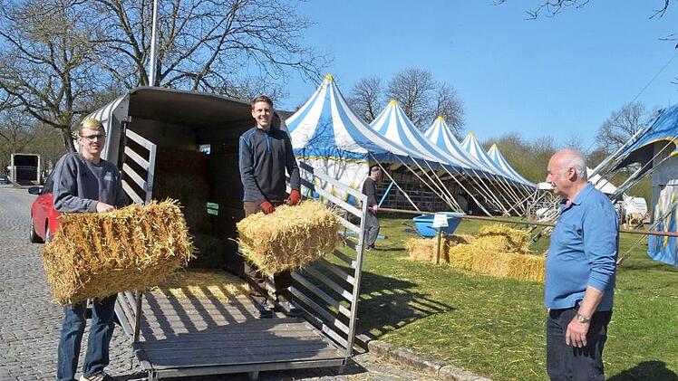 Toni Hübner (links) und Kevin Raab bringen Heu und Stroh für den Zirkus von Georg Frank (rechts). Foto: Rainer Lutz