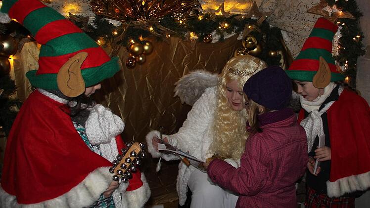 Kinder trugen dem Christkind (Judith Reitelbach) ihre Wünsche vor. Hier tut das die fünfjährige Hannah. Die beiden Wichtel Lena (links) und Finja (rechts) begleiteten das Christkind, das am Rathaus Platz nahm.
