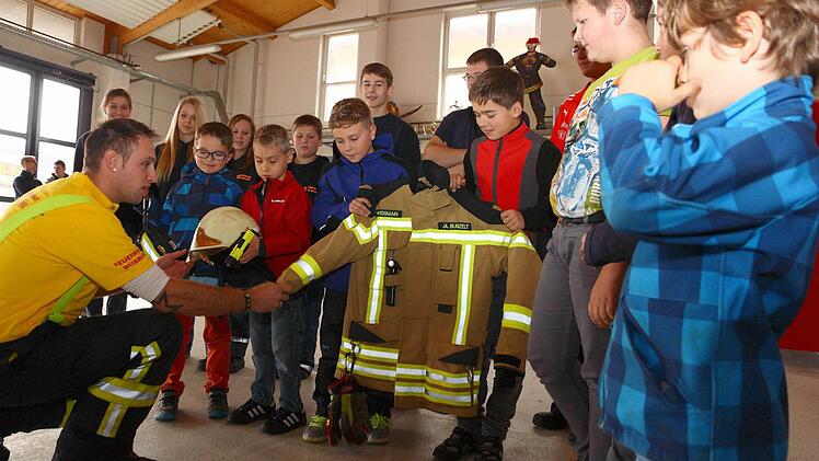 Was gehört zur Ausrüstung eines Feuerwehrmanns? Jan Bunzelt erklärt den interessierten Jungs Helm, Handschuhe und Co.