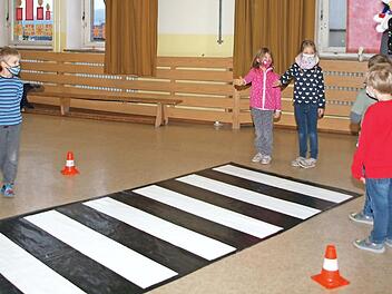 Die beiden Mädchen deuten mit der ausgestreckten Hand den Autofahrern (dargestellt durch Schüler) am Zebrastreifen an, dass sie die Straße überqueren wollen. Foto: Alfred Thieret