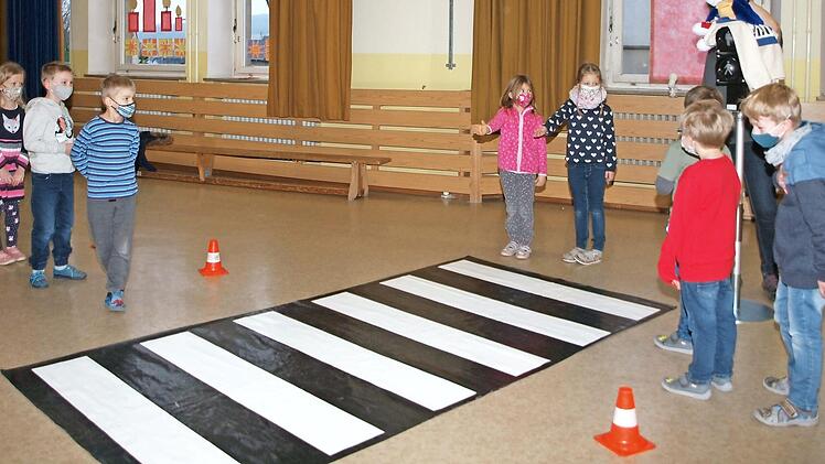 Die beiden Mädchen deuten mit der ausgestreckten Hand den Autofahrern (dargestellt durch Schüler) am Zebrastreifen an, dass sie die Straße überqueren wollen. Foto: Alfred Thieret