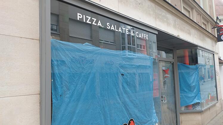 Geschlossenes Restaurant mit blauem Sichtschutz. Schilder zeigen "Pizza, Salate & Caffè". Abschiedsbotschaft und italienisches Herz-Logo auf dem Fenster.