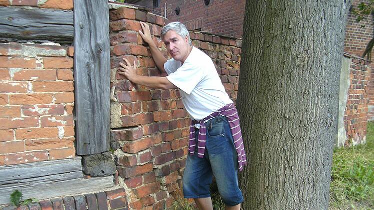 Udo Pörschke an der Mauer eines alten Guthofs von Göritz: Hier wurde sein Großvater mit anderen Kriegsgefangenen kurzfristig einquartiert. Foto: pr