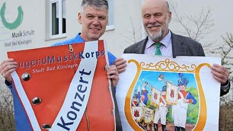 Bernd Hammer (links) zeigt das aktuelle Werbeplakat des Jugendmusikkorps, Michael Peter daneben zeigt ein 50 Jahre altes. Foto: Benedikt Borst