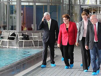 Überschuhe sind Pflicht, wenn man das Bad nur besichtigen will. Thermen-Geschäftsleiter Albert Döbele, Landtagspräsidentin Barbara Stamm, Marketingleiterin Gabriele Lippmann und Zweiter Bürgermeister Axel Dorscht (SPD) beim Rundgang im Thermalbad. Foto: Simone Bastian