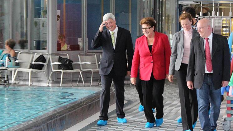 Überschuhe sind Pflicht, wenn man das Bad nur besichtigen will. Thermen-Geschäftsleiter Albert Döbele, Landtagspräsidentin Barbara Stamm, Marketingleiterin Gabriele Lippmann und Zweiter Bürgermeister Axel Dorscht (SPD) beim Rundgang im Thermalbad. Foto: Simone Bastian