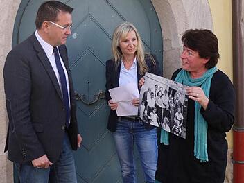Christiane Kolbet (r.) hat Adelsdorfs Bürgermeister Karsten Fischkal und Sandra Hammer von Karpfenland Travel ihren Spaziergang schon einmal vorgestellt. Dabei zeigt sie eine Fotografie, auf der die Familie Rindsberg zu sehen ist, als sie noch in Adelsdorf lebte. Foto: Pauline Lindner