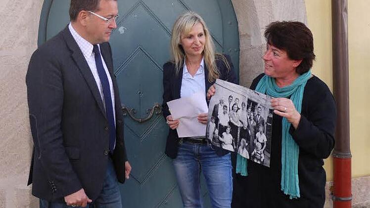 Christiane Kolbet (r.) hat Adelsdorfs Bürgermeister Karsten Fischkal und Sandra Hammer von Karpfenland Travel ihren Spaziergang schon einmal vorgestellt. Dabei zeigt sie eine Fotografie, auf der die Familie Rindsberg zu sehen ist, als sie noch in Adelsdorf lebte. Foto: Pauline Lindner