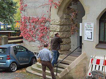 Zwei Mitarbeiter der Spurensicherung betreten am Montagvormittag das Alte Schützenhaus. Ob sie etwas gefunden haben, was zur Aufklärung des Falles beitragen kann, war bis gestern Abend nicht bekannt. Links und rechts vom Eingang sind Absperrungen zu sehen, die mit den derzeitigen Bauarbeiten am Gebäude zu tun haben. Fotos: Oliver Schmidt