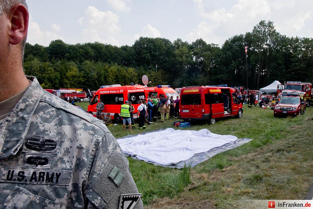 Ein US-Militär steht am 11.08.2015 bei Engelmannsreuth (Bayern) am Einsatzzentrum nahe der Absturzstelle eines Kampfjets. Bei Engelmannsreuth ist ein F-16 Kampfjet der US-Streitkräfte abgestürzt. Foto: Daniel Karmann/dpa