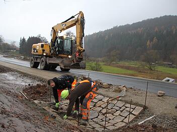 Zwei Bauarbeiter pflastern einen Regenablauf am Rande der neu gebauten Straße. Foto: Ulrike Müller