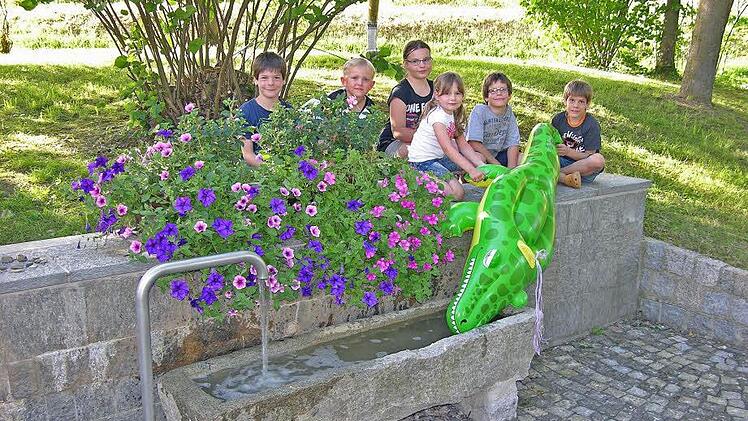Auf den Weickenbacher Nachwuchs übt das Wasser im neu gestalteten Dorfbrunnen seine Anziehungskraft aus. Foto: Klaus Oelzner