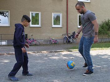 Ahmet Al-naib (27) spielt mit Haje (12) vor der Gemeinschaftsunterkunft Fußball. Foto: Alexander Hartmann