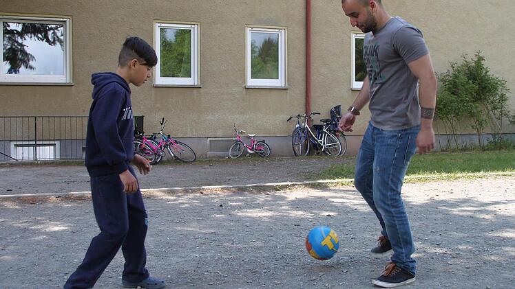 Ahmet Al-naib (27) spielt mit Haje (12) vor der Gemeinschaftsunterkunft Fußball. Foto: Alexander Hartmann