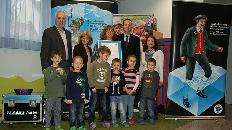 Der Kindergarten St. Josef Eltmann ist jetzt offiziell Wasser-Kita. Dr. Anne- Kathrin Jackel (hinten, Zweite von links) übergab offiziell die Urkunde und die Experimentierkiste an Leiterin Karin Unsleber. Die Roll-Ups im Hintergrund zeigen eindrucksvoll den Unterschied der Niederschläge im Voralpenraum (links) und in Unterfranken. Foto: Sabine Weinbeer