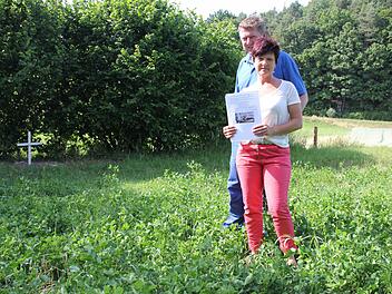 Karin Müller und Roland Söldner mit den Plakaten, die sie aufgehängt hatten, um ihren "Lucky" wieder zu finden. Er lag tot auf diesem Acker und wurde dort auch vergraben, wie das Kreuz zeigt. Im Hintergrund im Tal erkennt man am Waldsaum einen Hochsitz. Fotos: Ralf Kestel