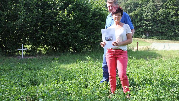 Karin Müller und Roland Söldner mit den Plakaten, die sie aufgehängt hatten, um ihren "Lucky" wieder zu finden. Er lag tot auf diesem Acker und wurde dort auch vergraben, wie das Kreuz zeigt. Im Hintergrund im Tal erkennt man am Waldsaum einen Hochsitz. Fotos: Ralf Kestel