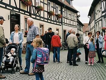 Eine Gruppe von Menschen unterschiedlichen Alters in einem fränkischen Dorf. Manche unterhalten sich.