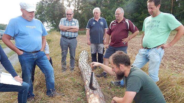 Förster Fabian Kowollik zeigt den Waldbauern den Stamm einer kranken Kiefer.