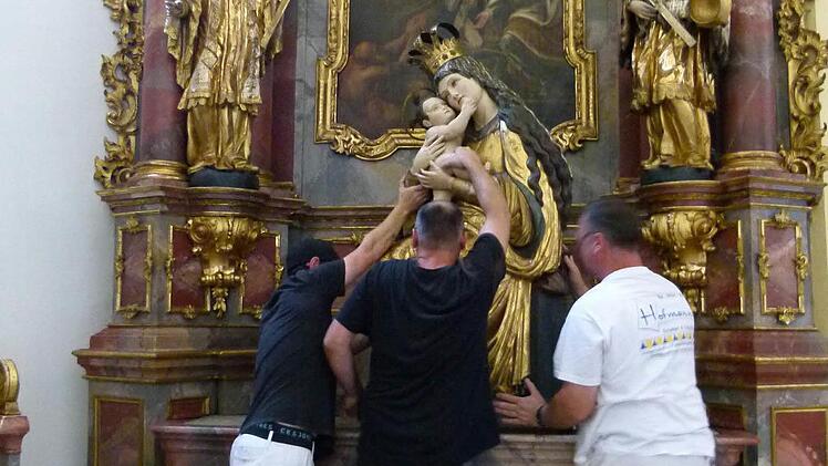 Mit vereinten Kräften wird die Gottesmutter Maria wieder an ihren angestammten Platz gehievt.
