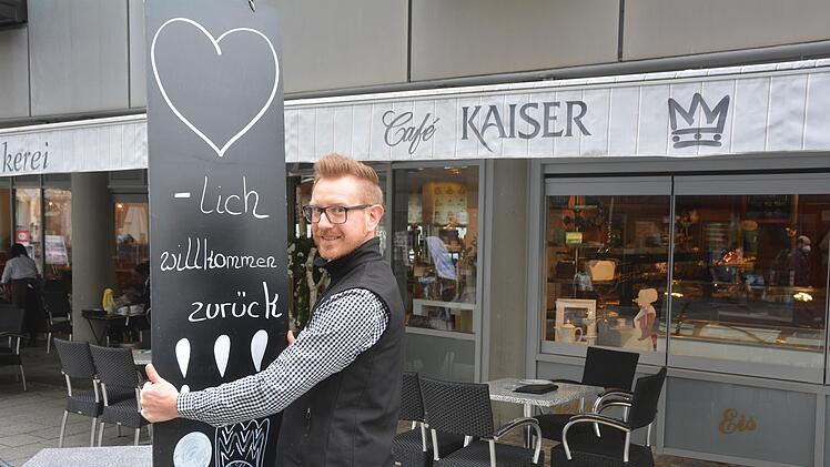 Nicolas Borst vom Café Kaiser stellt ein Hinweisschild auf.