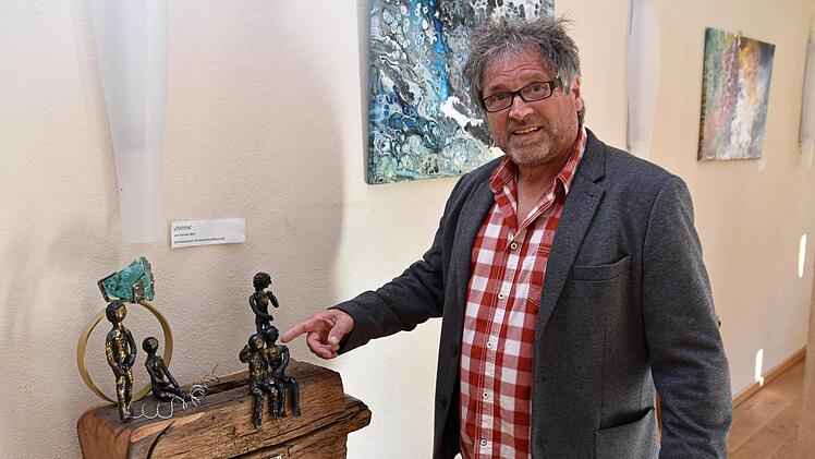 Bei der Vernissage im Weinhaus Schaffner erläuterte der Maler und Objekt-Künstler Hannes Betz seine Arbeiten. Im Bild die Skulptur "Flüchtling", bei der der Diamantring die westliche, reiche Welt symbolisiert, die sich mit Stacheldraht gegen die Flüchtlinge abschottet. Dennoch nehmen sich zwei Menschen in den Arm (im Vordergrund).