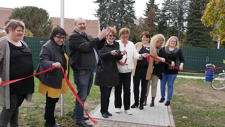 Bürgermeisterin Elke Protzmann, Leiterin Adriana Sacagiu (Fünfte und Vierte von rechts) machten den Weg frei, damit die Hausbewohner sich frei im  geschützten Außenbereich bewegen können. Um die Ecken herum gibt es überall  Ein- und Ausgänge, damit die Menschen sich nicht eingesperrt fühlen. Mit dieser Erweiterung des Gartens werden den Bewohnern lange, runde Wege  angeboten, um ihrem Bewegungsdrang nachzukommen.  Foto: Manja von Nida