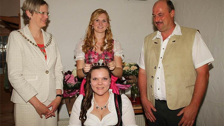 Bürgermeisterin Christine Konrad und Rainer Müller beobachten, wie Mona Wiedermann Julia Müller die Krone der Neuseser Weinprinzessin aufsetzt. Foto: amo