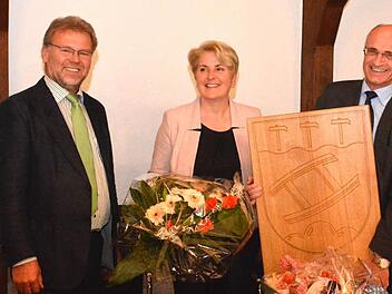 2. Bürgermeister Werner Wunderlich (links) verabschiedete sich namens des Marktgemeinderats Maroldsweisach von Bürgermeister Wilhelm Schneider (rechts) mit einem Holzwappen der Gemeinde. Blumen durfte Gattin Larissa Schneider entgegennehmen. Foto: Schmidt