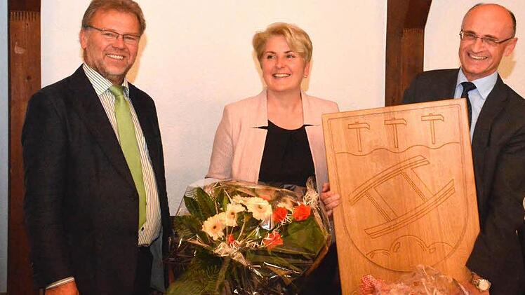 2. Bürgermeister Werner Wunderlich (links) verabschiedete sich namens des Marktgemeinderats Maroldsweisach von Bürgermeister Wilhelm Schneider (rechts) mit einem Holzwappen der Gemeinde. Blumen durfte Gattin Larissa Schneider entgegennehmen. Foto: Schmidt