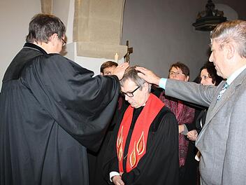 Dekan Martin Ost (l.) und die Mitglieder des Kirchenvorstands entpflichteten Ulrich Bauer-Marks durch Handauflegen von seinen Aufgaben. Foto: Sonja Werner