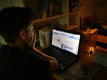 Ein Junge hält sich vor seinem Laptop beim Betrachten der Facebook-Seite die Hände vor das Gesicht. Foto: Oliver Berg/dpa