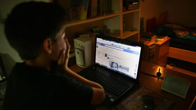Ein Junge hält sich vor seinem Laptop beim Betrachten der Facebook-Seite die Hände vor das Gesicht. Foto: Oliver Berg/dpa