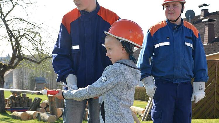 Finn-Luis (Mitte) fühlt sich wie ein richtiger Feuerwehrmann. Samuel Schmitt (links) und Maximilian Fösel (rechts) zeigen ihm, wie man richtig mit dem Schlauch umgeht. Foto: Björn Hein