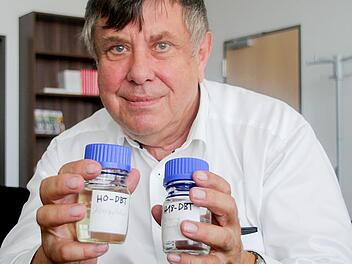 Wolfgang Arlt zeigt zwei Gläser, gefüllt mit der LOHC-Trägerflüssigkeit. Rechts ist Wasserstoff gebunden.  Foto: Matthias Litzlfelder