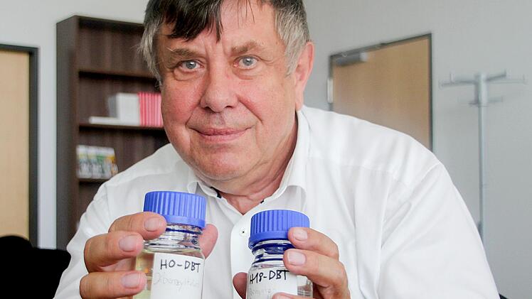 Wolfgang Arlt zeigt zwei Gläser, gefüllt mit der LOHC-Trägerflüssigkeit. Rechts ist Wasserstoff gebunden.  Foto: Matthias Litzlfelder
