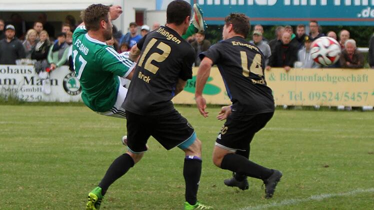 Der Sander Florian Pickel (links) erzielt aus der Drehung heraus um die beiden Erlanger Aubrey Dolan (Nr. 12) und Thomas Wilke (Nr. 14) aus sechs Metern das 1:0 für Sand.