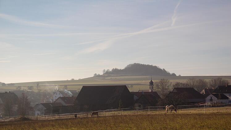Blick auf Hetzlos im Jahr 2014 mit der markanten Kirchturmspitze und Blick auf den Büchelberg