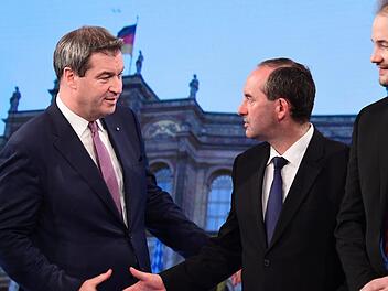 Markus Söder (CSU, l), Ministerpräsident von Bayern, gibt Hubert Aiwanger, Spitzenkandidat und Partei-Chef der Freien Wähler in Bayern, während der Wahl bei einer Fernsehsendung die Hand. Rechts steht der AfD-Vorsitzende Martin Sichert. Foto: Peter Kneffel/dpa-Pool/dpa