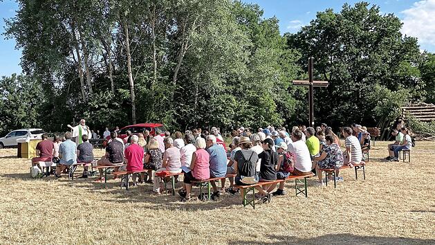 Selbst der von der Sonne beschienene Teil beim Gottesdienst war voll besetzt. Auf der rechten Seite, neben dem gro&szlig;en Metallkreuz, der gro&szlig;e aufgeschichtete Holzhaufen f&uuml;r das anschlie&szlig;ende Johannisfeuer.