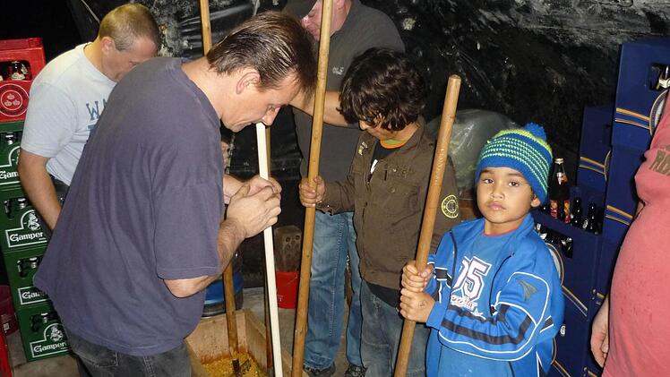 In Holzbottichen zerkleinern die Wallenfelser mit alten Spezialwerkzeugen Erdkohlrabi, wie in Wallenfels die Steckrüben genannt werden, Möhren, Lauch, Wirsing und Kraut. Gilbert Weiß, Markus Weiß (linke Seite), Bastian und Max Buckreus sowie Manfred Stöcker (rechte Seite von vorne nach hinten) sind mit Feuereifer bei der Sache. Fotos: Sonja Adam