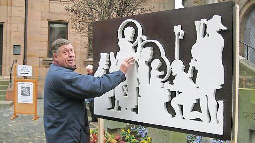 Heribert Nickl stellt die Tafel zur Krippenausstellung auf.