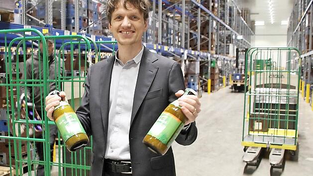 Lukas Nossol, Sohn des Firmengründers und Dennree-Marketingleiter, steht im Zentrallager in Töpen und hält zwei Flaschen mit Vollmilch der Hausmarke. Das Sortiment hier umfasst 13 000 Artikel. Foto: Matthias Litzlfelder